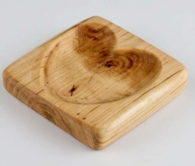 A small square dish lifted from a single block of figured maple, the heartwood reading like two hearts in the well.