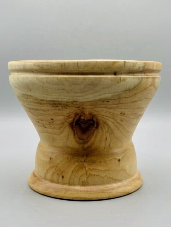 A pedestal cup, the lathe holding a knot at center as a small dark eye in the figure.