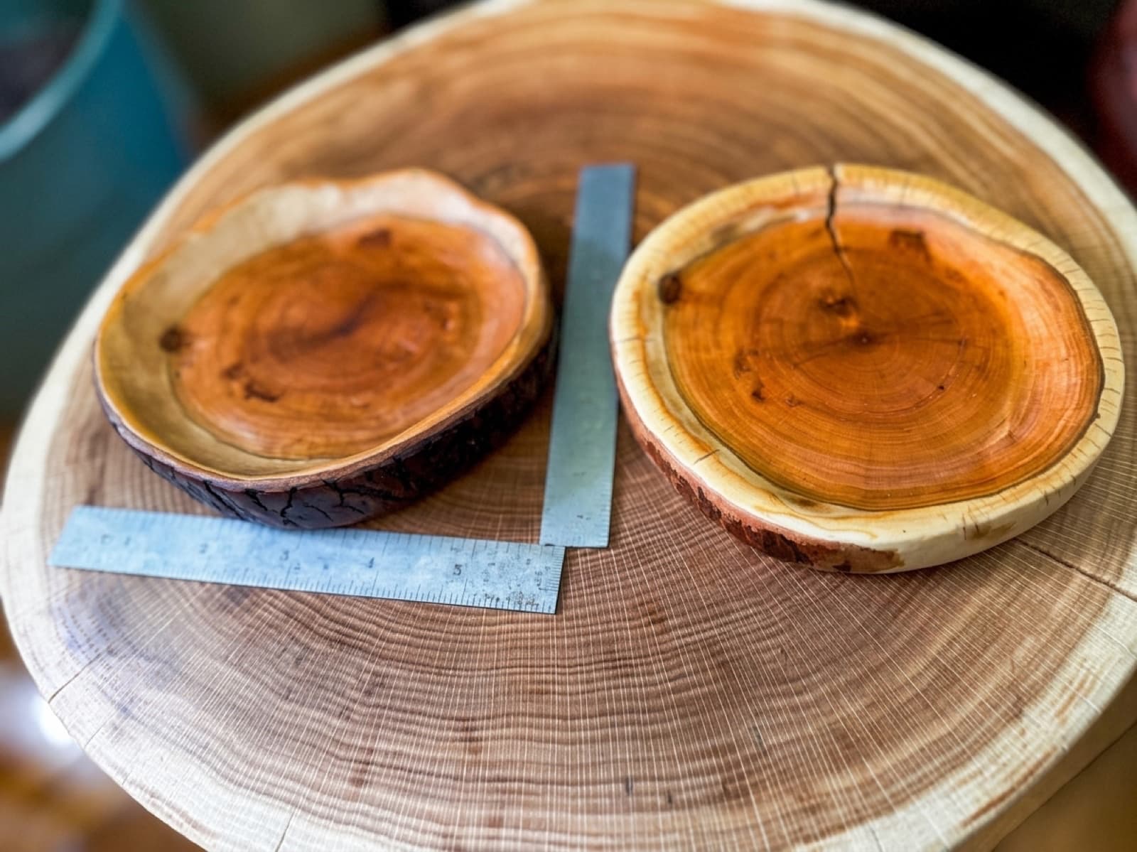 Two shallow cherry dishes resting on the end-grain slab they came from, machinist's rules laid alongside for scale.